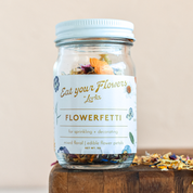 Glass jar full of colorful flower petals. White label and a white lid. 