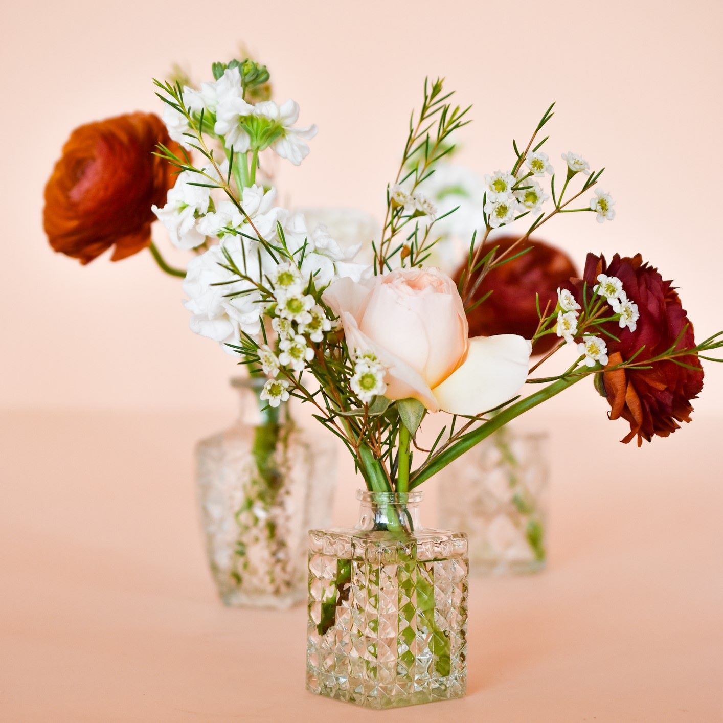 Bud vases with holiday-inspired pink and deep burnt red flowers