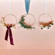 an arrangement of 3 different wreaths on gold frames with different colored dried flowers and ribbon