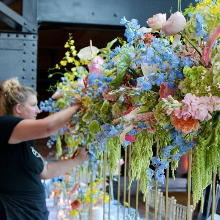 A Blossom Team Member works on an elaborate and gorgeous elevated centerpiece for the head table