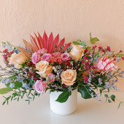 roses, spray roses, delphinium, ginger and palm fans in a colorful arrangement